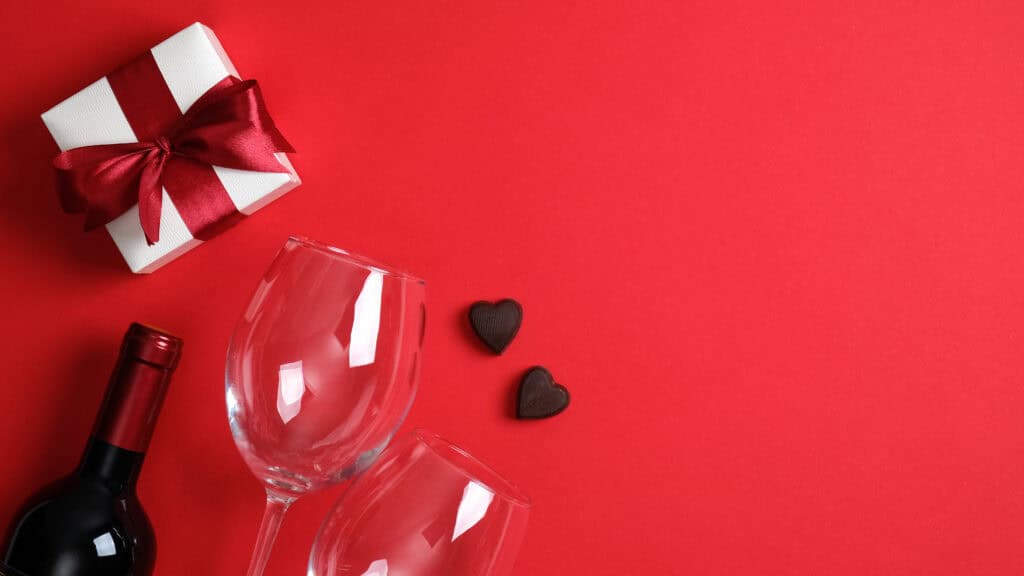 valentine's day dinner concept. top view table with setting for romantic dinner, bottle of wine champagne, glasses, white gift box, candies. valentines card. valentines day banner with copy space.